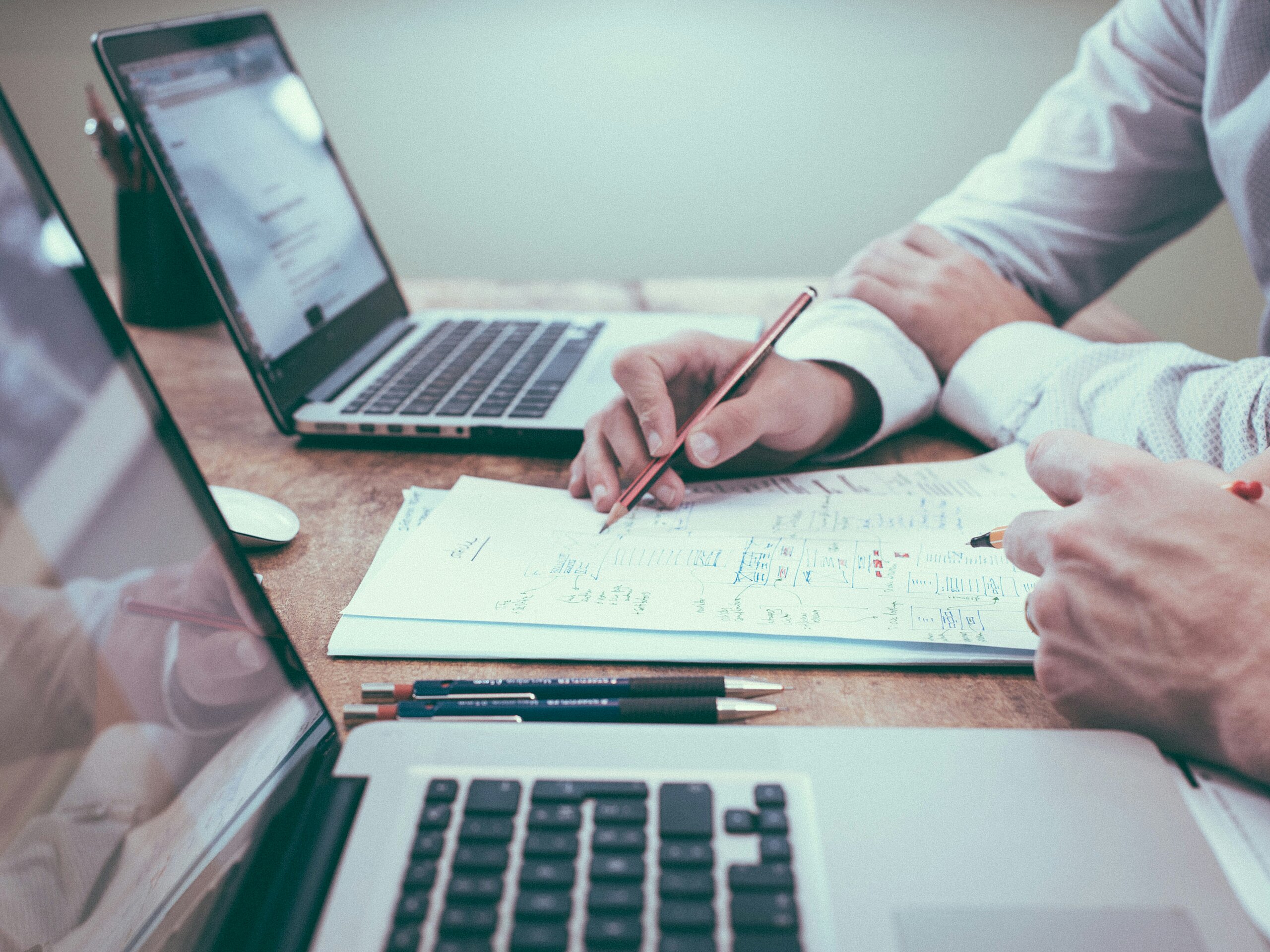 Two people working at computers on a desk.